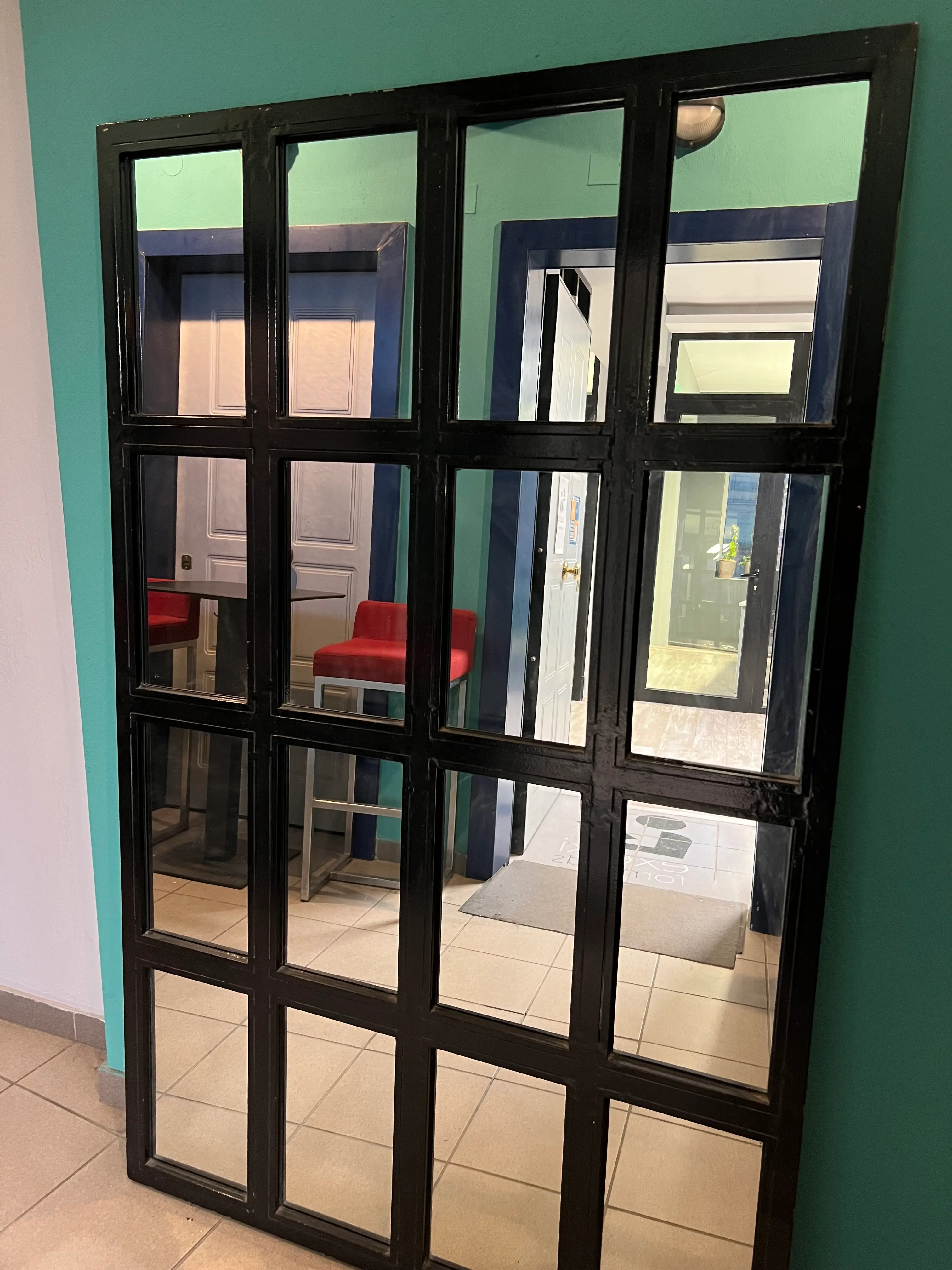 A black-framed mirror reflecting the entrance to Exelixi For Minds.